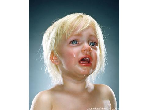 Photo of the unclothed torso of a short-haired, blond, crying toddler with blue background