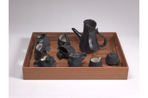 handmade tea set comprised of 6 cups (with three different shapes), tea pot with two handles, creamer and sugar dish with lid in black glazed and/or black clay; nside of cups is painted by hand in black, white, and greyscale colors inspired by the Black Lives Matter banners on Smith campus houses, as part of the commission "An Imposing Number of Times" (2020-22)