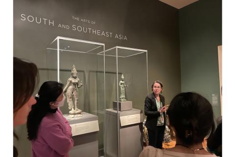 woman standing before students at the front of the south and south east asia exhibit