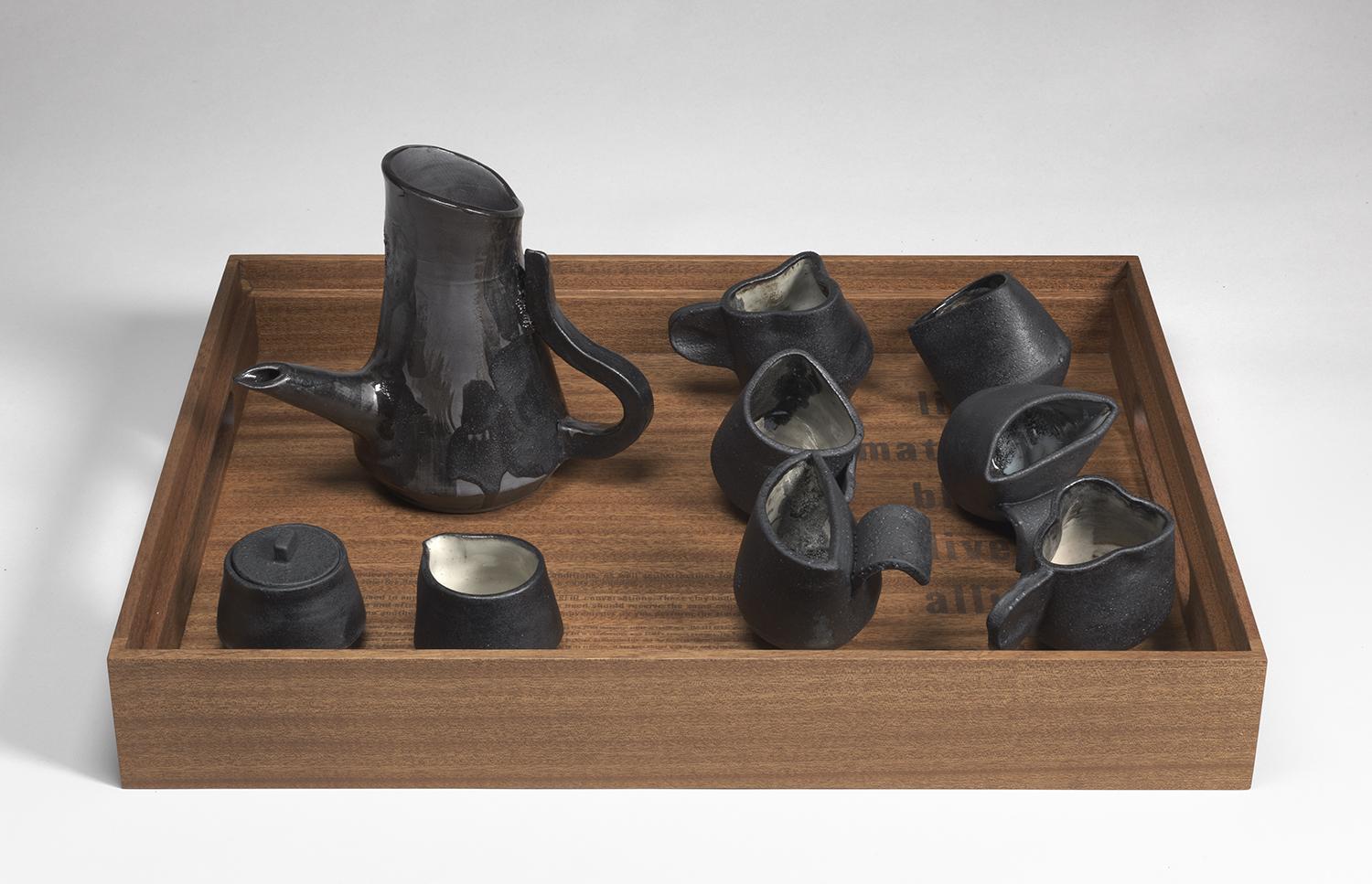 Black clay tea set on a wooden tray