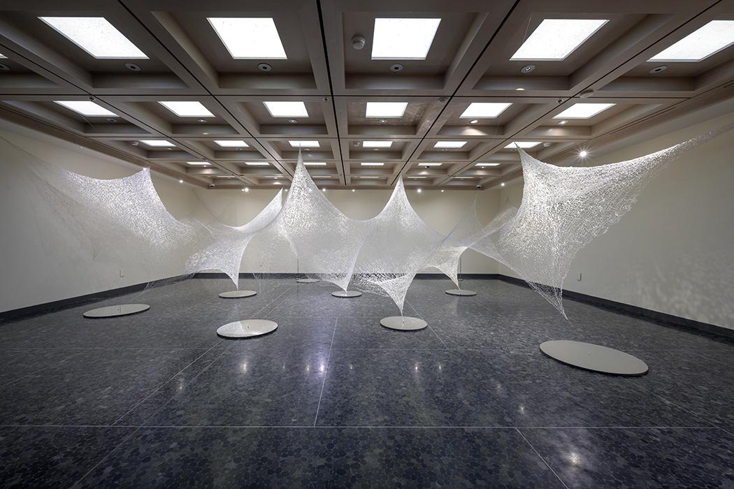 Photo of a web-like artwork hanging from floor to ceiling