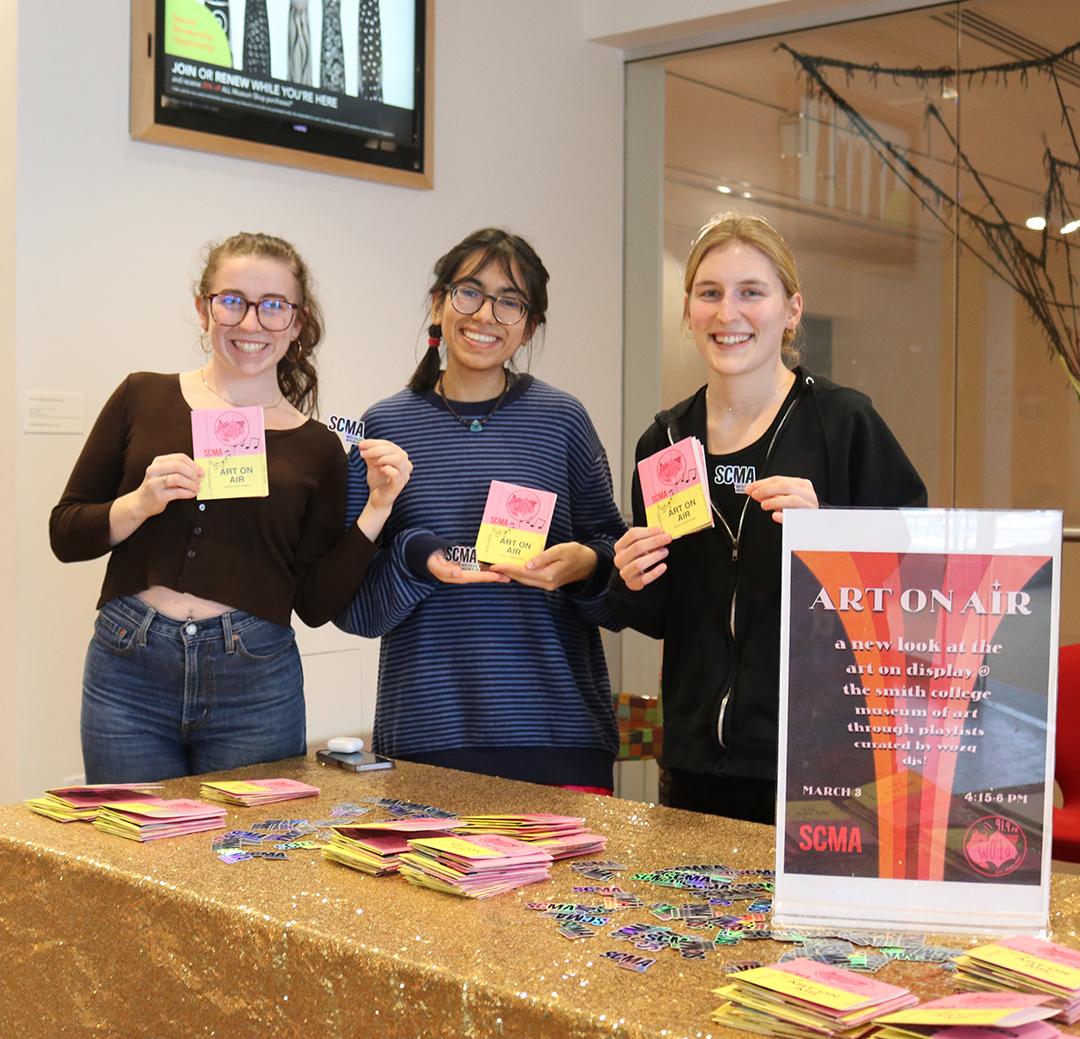Three students standing behind a table at an Event called Art on Air