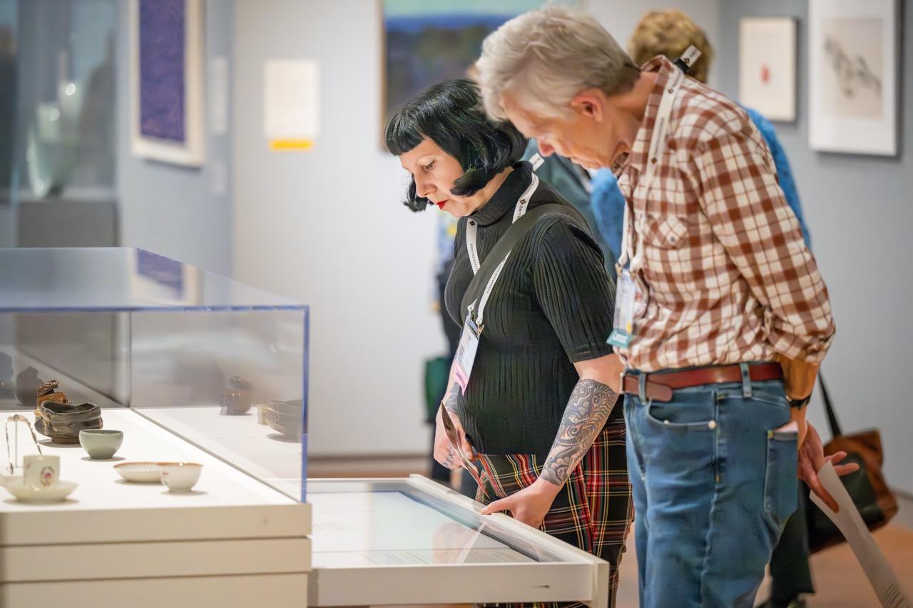 Two people looking at artwork in a drawer with a cabinet of drawers in a gallery