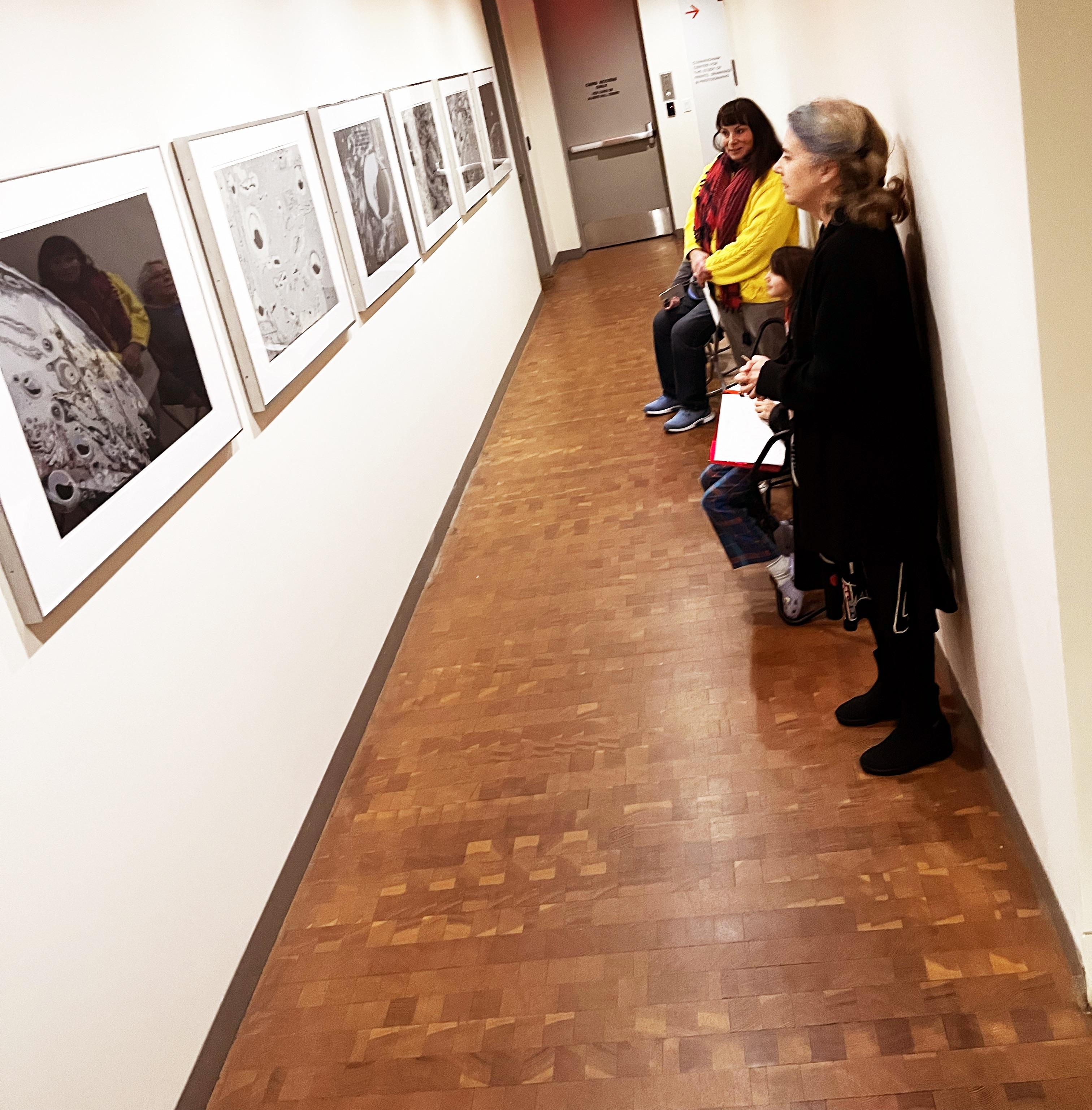 Corridor of several people looking at art hanging on the walls
