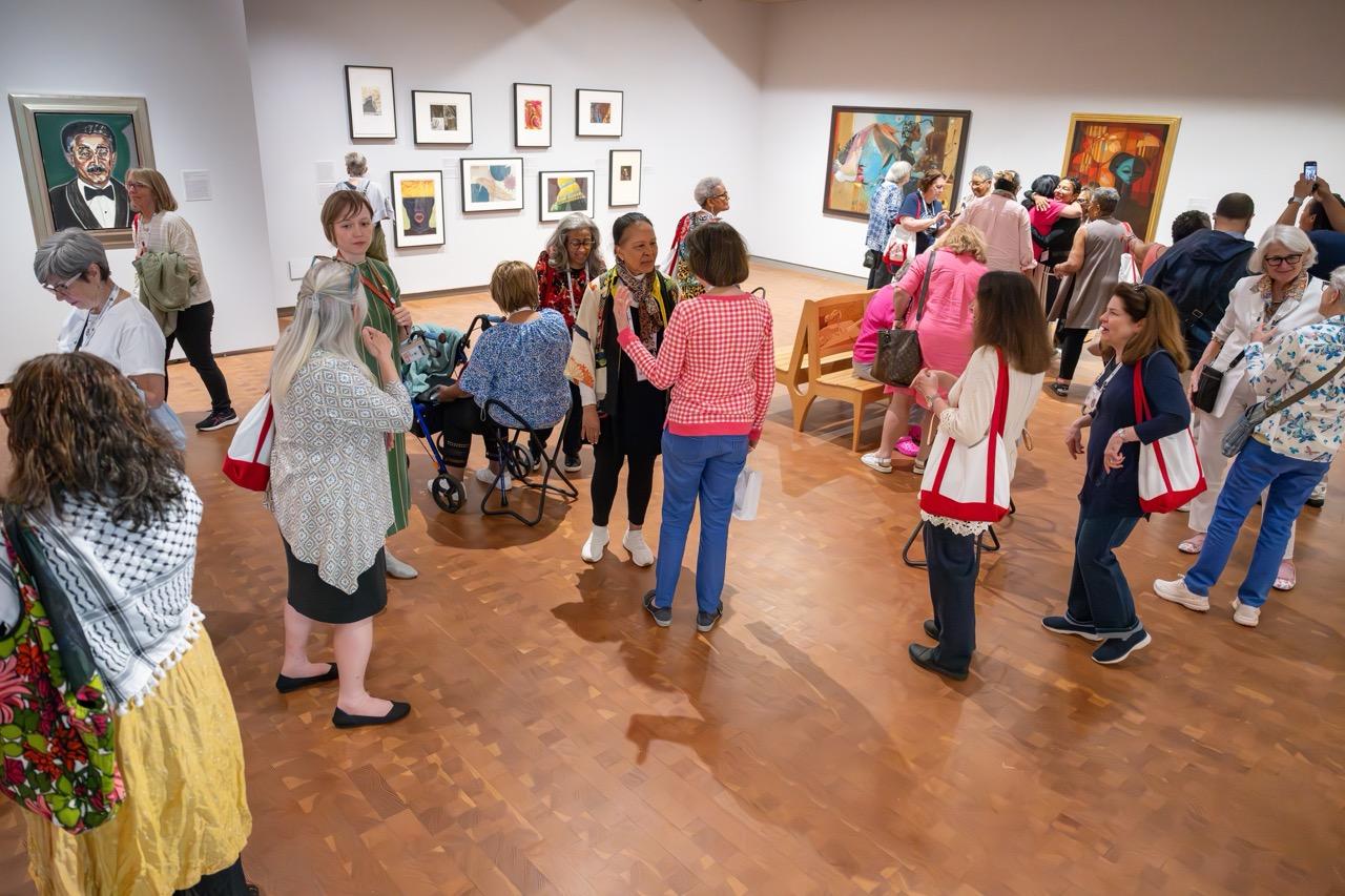 Gallery full of people talking and looking at art