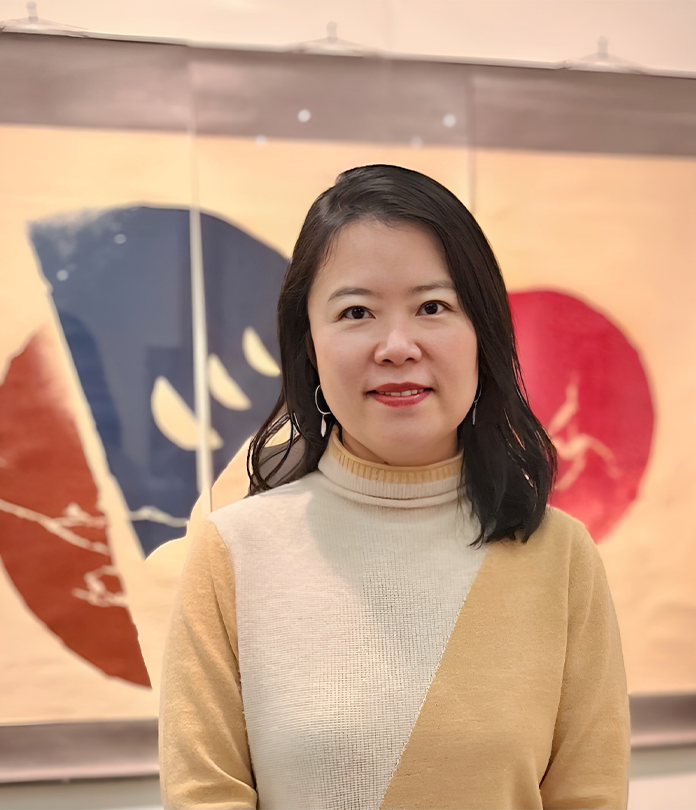 Close up of a person with dark hair standing in front of a painting