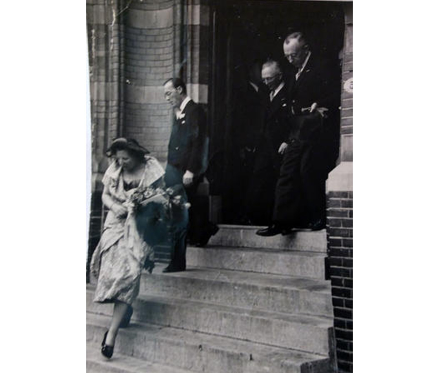 woman walking down a set of stairs, followed by three men in suits