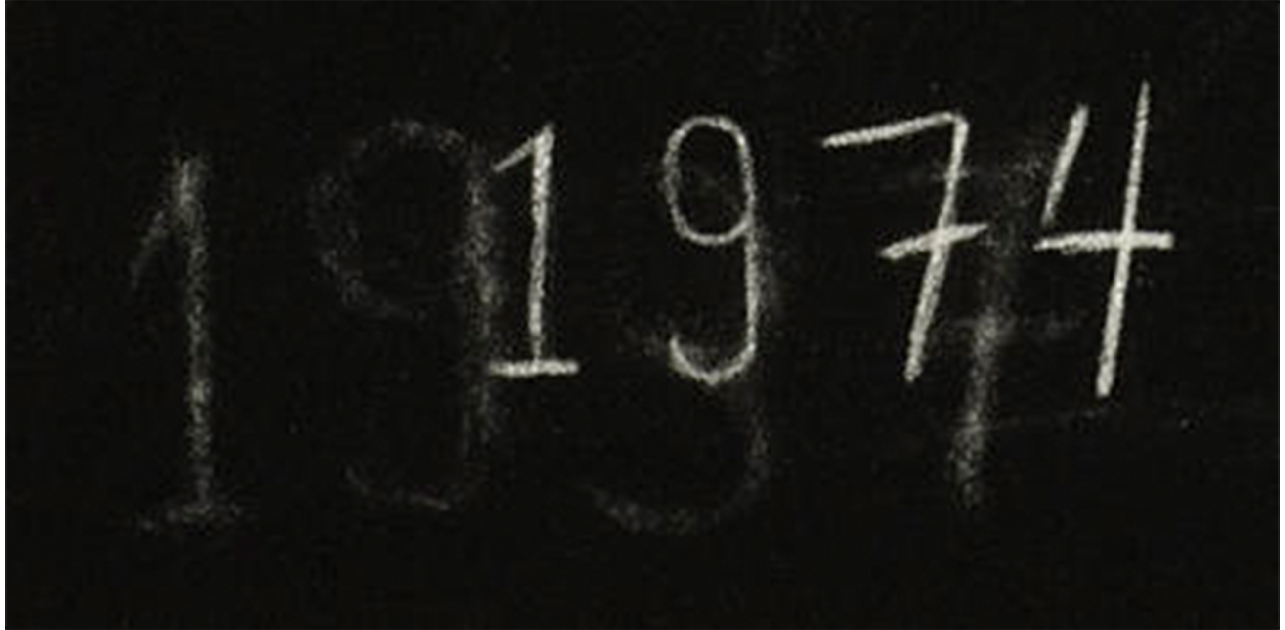 black chalkboard with "1974" written on it in white. to the left of that, another version of the "1974" written in white, but faded as though it has been erased