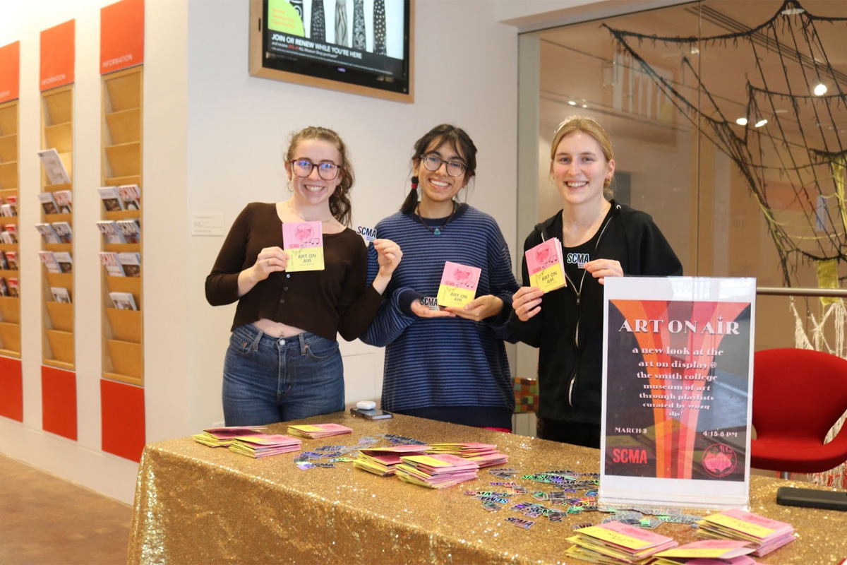 "three board members of WOZQ holding up the zine handed out to visitors"